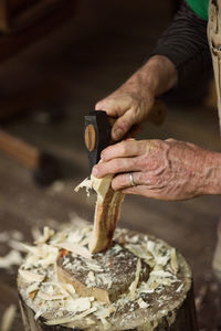 Cropped imager of carpenter shaping wood with chisel hammer at workshop