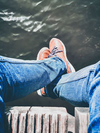 Low section of man sitting on pier over lake