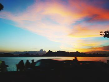 Silhouette of people on landscape against cloudy sky