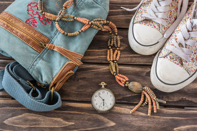 Close-up of shoes with pocket watch and handbag on table