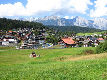 Village field by mountains against sky