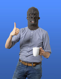 Midsection of man holding coffee cup against blue background