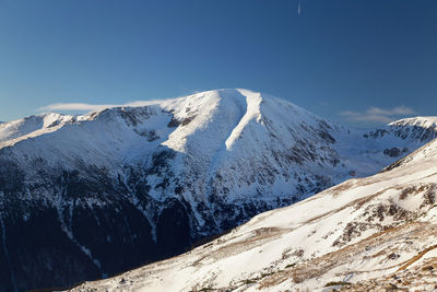 Scenic view of snowcapped mountains against clear blue sky