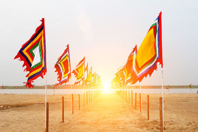 Flags on beach against sky during sunset