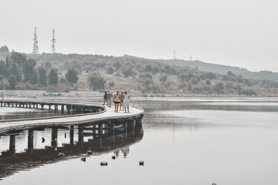 People on lake against clear sky