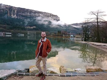 Portrait of man standing by lake against mountain