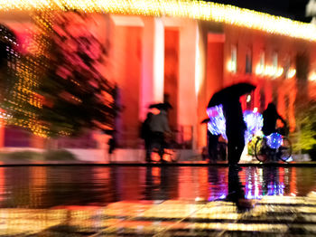 Reflection of illuminated woman in water at night