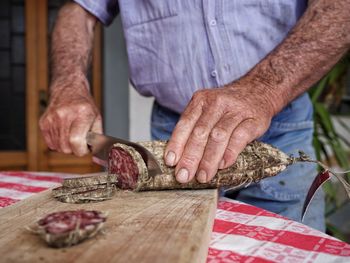 Midsection of man working on cutting board