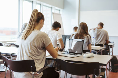 Rear view of young students learning in classroom at university