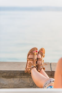 Low section of woman on retaining wall against sea