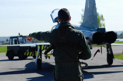 Rear view of man standing by airplane on road