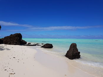 Rocks on beach against blue sky