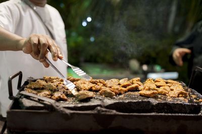 Close-up of man preparing food on barbecue grill
