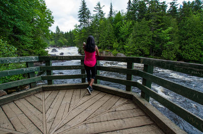 Rear view of woman standing on footbridge