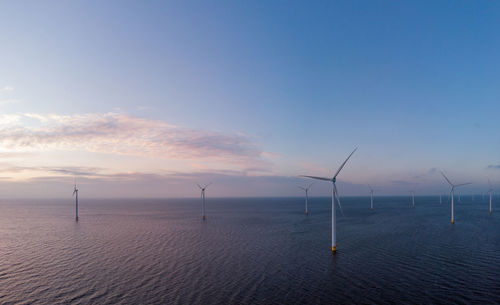 Wind turbines in sea against sky during sunset, windmill turbines in the netherlands 