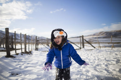 Cheerful girl playing in snow during winter