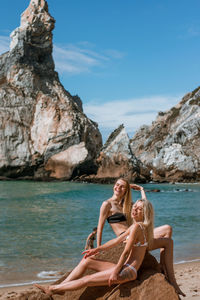Friends sitting on rock by sea
