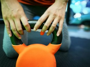 Midsection of woman holding kettlebell in gym