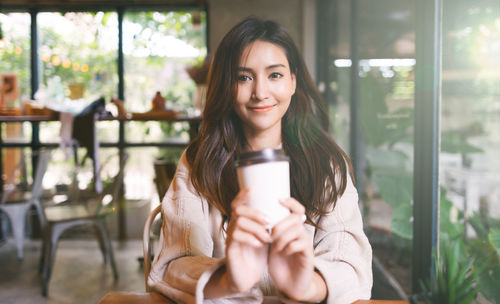 Portrait of smiling young woman holding smart phone