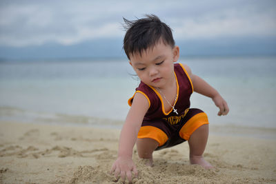 Boy playing on beach against sky