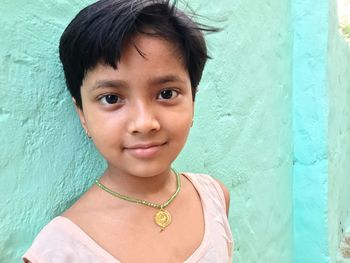 Portrait of cute girl smiling against wall