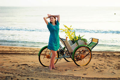 Full length of woman sanding by bicycle on beach