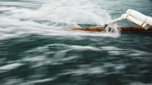 Cropped image of outrigger boat sailing in sea