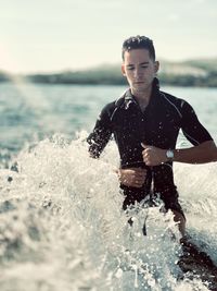 Young man standing in sea against sky