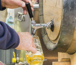 Close-up of hands pouring beer from barrel