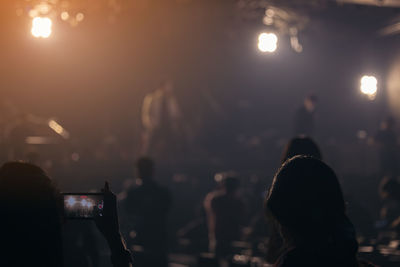 Recording a concert with mobile phone, silhouette of hands with smartphone