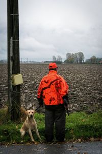 Rear view of man with dog against sky