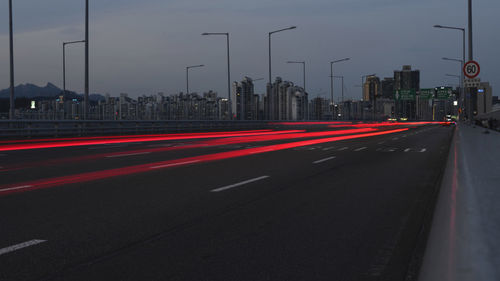 Light trails on city street against sky