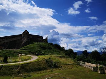 Built structure on landscape against cloudy sky