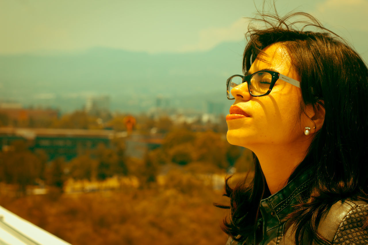 one person, focus on foreground, young women, real people, eyeglasses, young adult, outdoors, leisure activity, headshot, beautiful woman, lifestyles, day, close-up, nature, sky