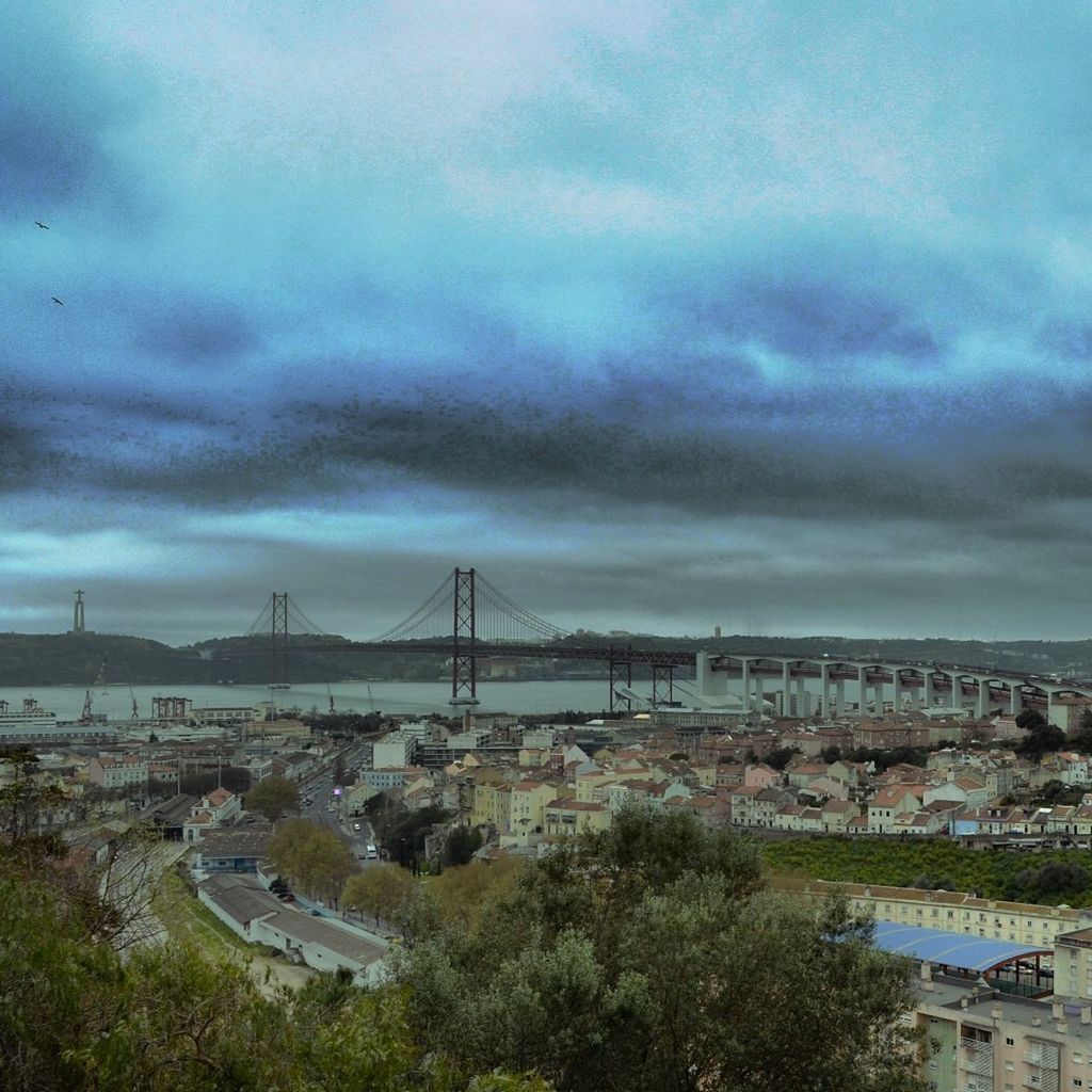 architecture, built structure, building exterior, sky, cloud - sky, city, cloudy, water, cityscape, river, high angle view, connection, bridge - man made structure, transportation, cloud, weather, residential district, overcast, residential building, tree