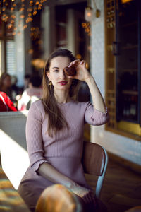 Girl in a pink dress sits on a chair in a pink dress and holds a cookie