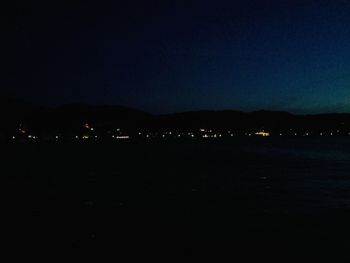 Silhouette landscape against clear blue sky at night