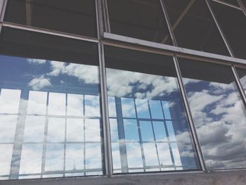 Low angle view of modern building against cloudy sky