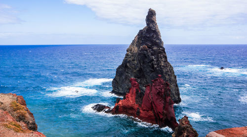 Rock formation on beach against sky