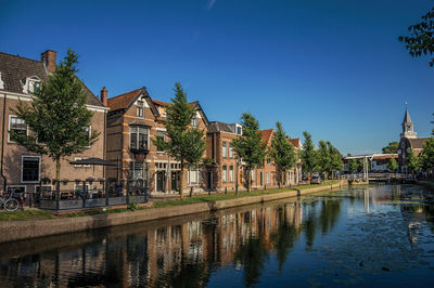 Reflection of building in lake against clear blue sky