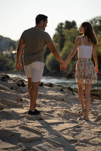 Rear view of couple walking on sand