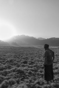 Rear view of man standing on land against sky