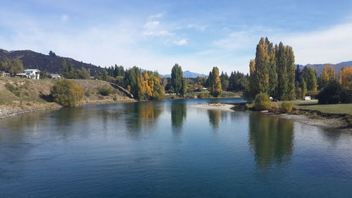 Scenic view of river by trees against sky