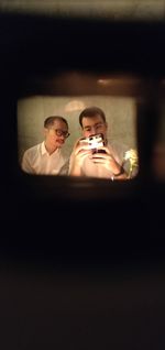 Man taking selfie in mirror reflection with friend