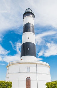 Low angle view of lighthouse by building against sky