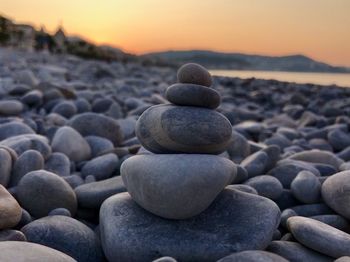 Stack of stones at beach during sunset