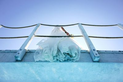 Low angle view of bride against blue sky