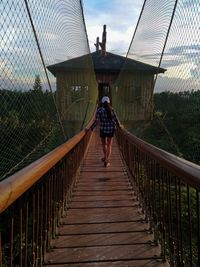 Rear view of woman walking on footbridge