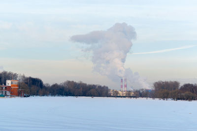 Smoke emitting from factory against sky during winter