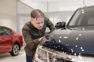 Side view of man using mobile phone while standing in car